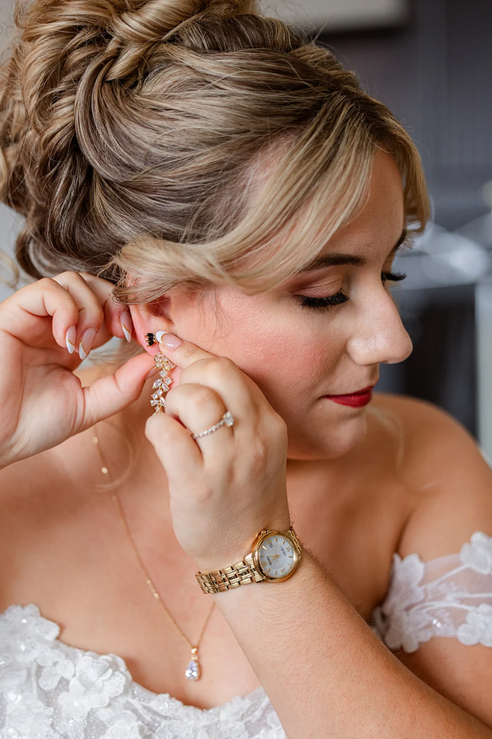 Blonde bride putting on earring