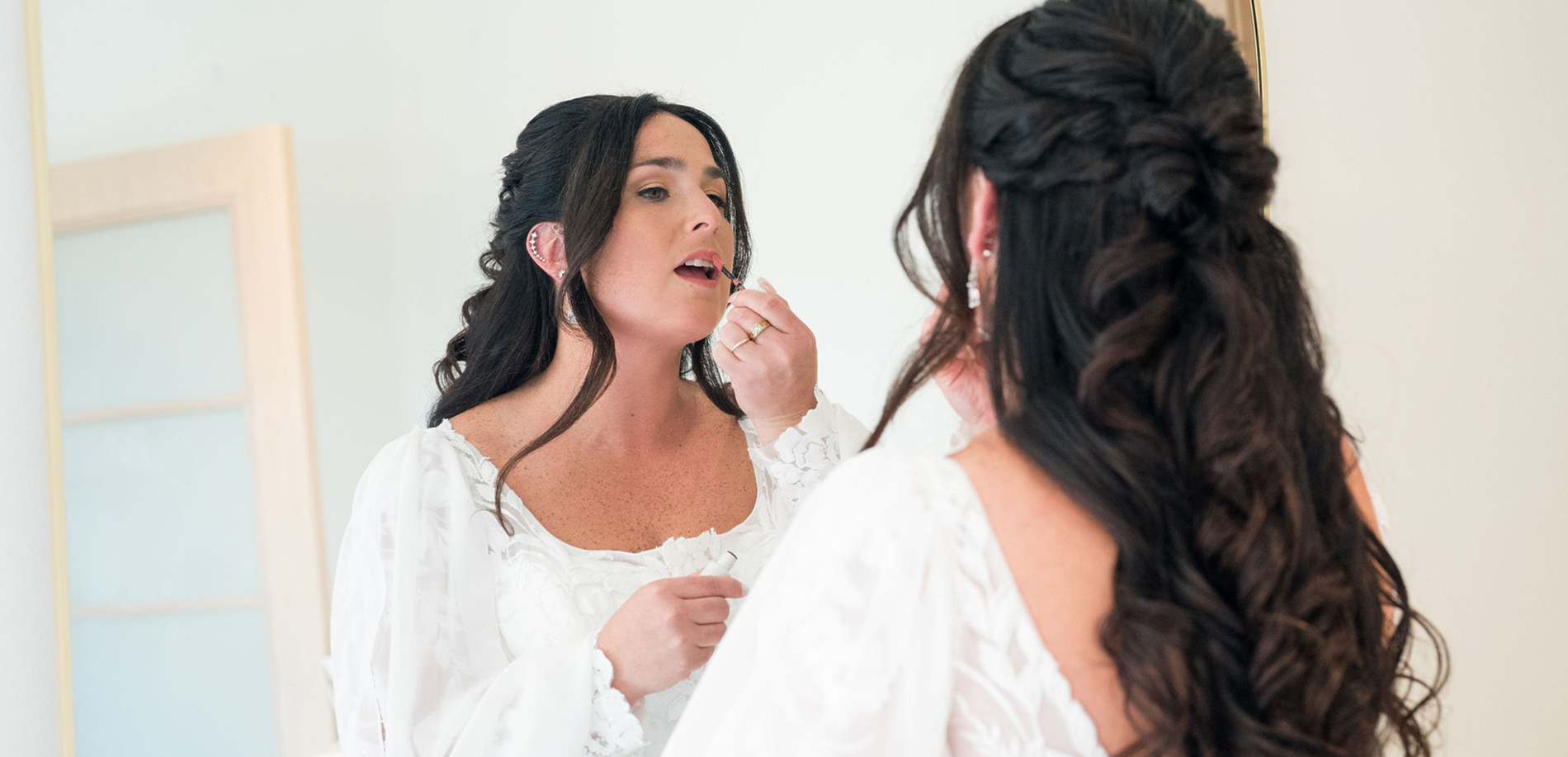 Bride putting on makeup in mirror