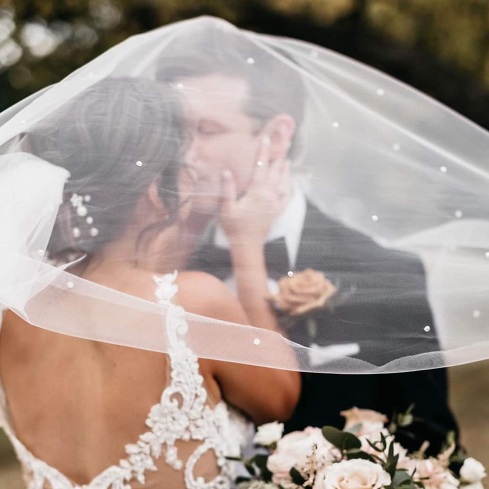 Bride and groom kissing under veil