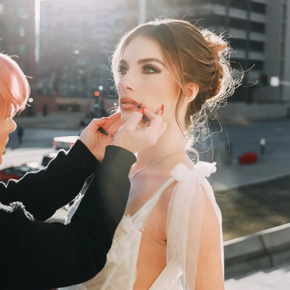 Bride in city having lipstick applied