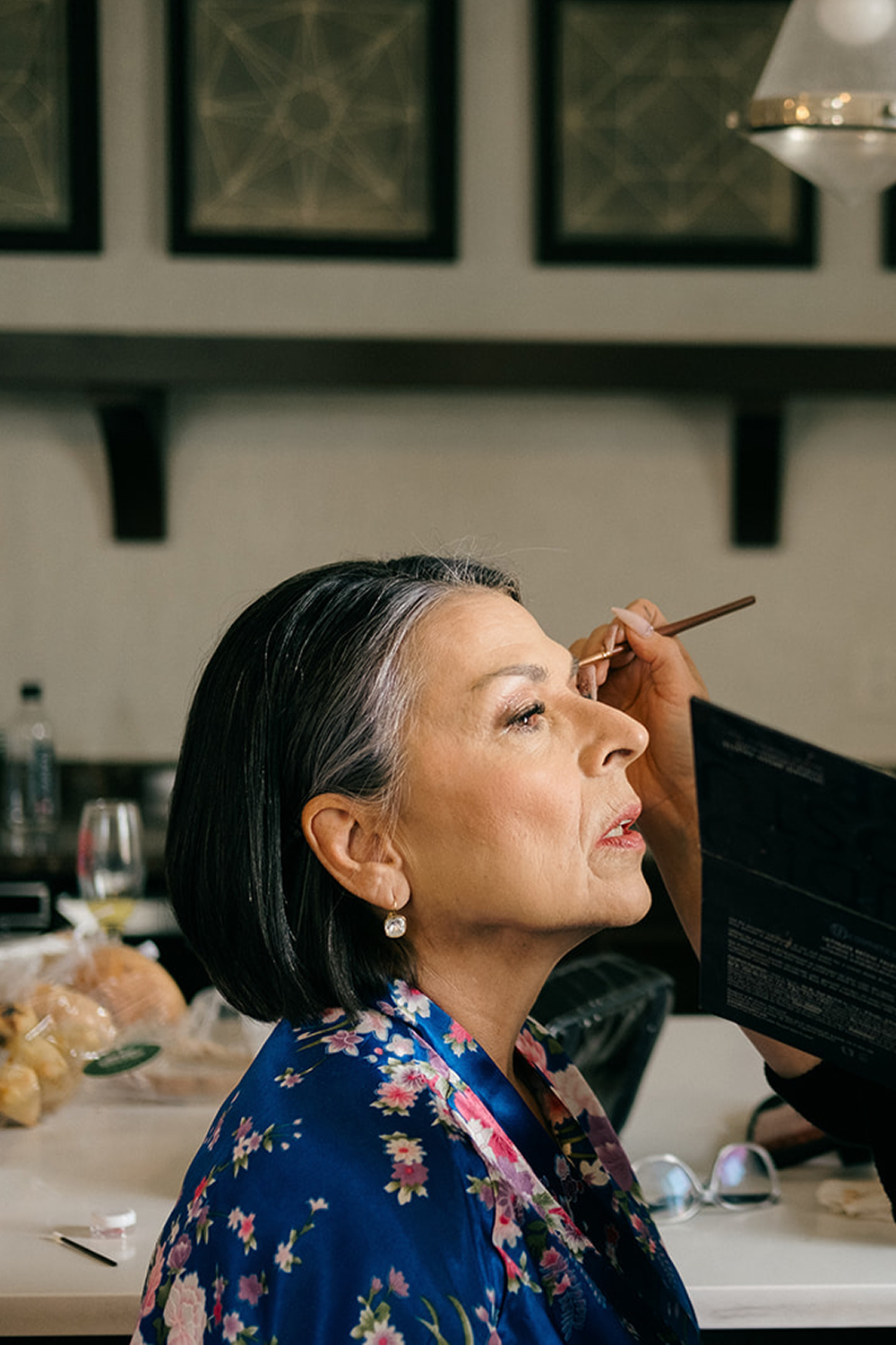 Brunette bride in blue robe getting makeup applied